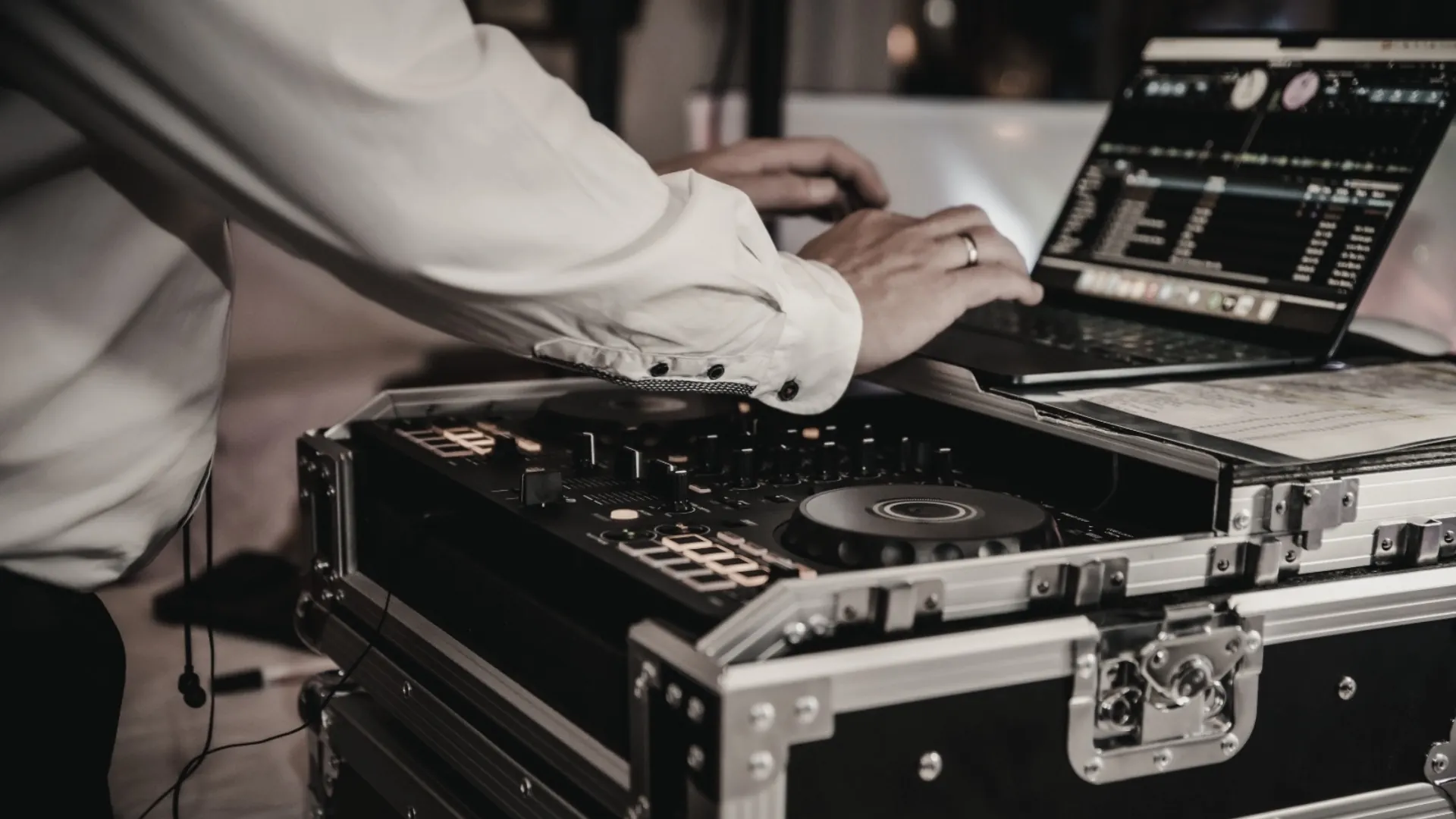 DJ arbeitet mit Laptop und Mischpult, nutzt das Party DJ Setbook zur Strukturierung von Sets für harmonisches Live-Mixing.